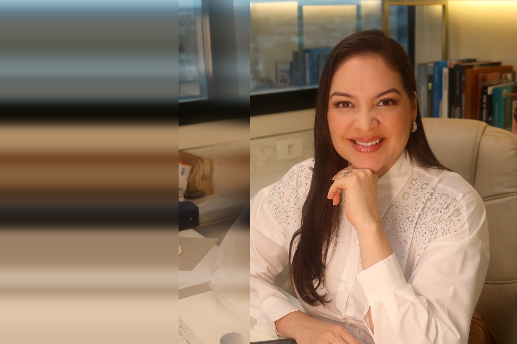 Dra. Aline Záu à mesa de atendimento no consultório, com o dermatoscópio ao lado.